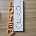 Close-up of LOVE letters and heart silicone mold with finished orange resin samples - LOVE