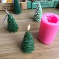 Detailed macro view of a pink silicone mold and green Christmas tree candles on a wood table. - Christmas Tree
