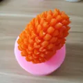 Close-up detail of a pinecone-shaped silicone mold with finished orange candle piece - Pinecone Shape (3523)