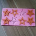 Overhead view of a pink 8-cavity star-shaped silicone mold with orange star-shaped inserts - 8-Cavity Star Style / Pink