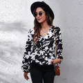 Elegant black and white floral print blouse with V-neck and lantern sleeves on model - Large White Floral Black Background