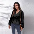 Detail einer schwarzen V-Ausschnitt-Schößchenbluse mit eleganten Laternenärmeln. - Schwarz