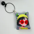 Primer plano de un colgante de lona para bolso con una chica de dibujos animados. - Chica de Dibujos Animados con Sombrero Amarillo