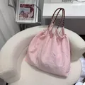 Detail view of a pink textured floral tote bag with stylish rope handles on a white chair - M / Ribbed Pink