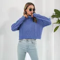 Close-up of a blue cable-knit turtleneck cropped sweater worn by a model in a studio. - S / Tops / Blue