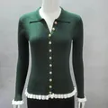 Detailed view of dark green ribbed cardigan with gold buttons and white ruffle trim - Green