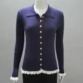 Close-up detail of a navy blue ribbed knit cardigan featuring gold buttons and ruffle trim - Navy Blue
