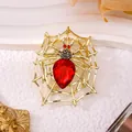 Close-up detail of a vintage Halloween spider brooch with a large red teardrop gemstone. - Gold Spider Web Brooch