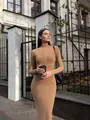 Model wearing elegant camel ribbed knit mock neck maxi dress in an outdoor city setting - S / Dresses / Khaki