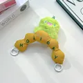 Detail view of a green plush monster charm with a yellow embroidered 'HOLIDAY' handle. - Ginger Yellow Curved Handle