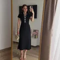 Full length lifestyle view of an elegant black ribbed midi dress with contrast polo collar. - S / Dresses / Black