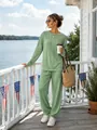 Close-up detail of a women's green cable-knit sweater and pants set in an outdoor setting. - Green