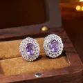 Macro view of oval purple gemstone earrings displayed inside a velvet-lined wooden box - Natural Amethyst Stud Earrings