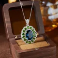 Macro detail of S925 silver pendant with oval blue topaz and green gemstone halo setting - Natural London Blue Topaz