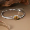 Close-up of silver bangle with round yellow citrine gemstone and sparkling white crystals - Natural Citrine Bracelet
