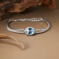 Detailed macro shot of a S925 silver bracelet featuring a halo-set round blue topaz gem - Natural Topaz Bracelet