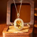 Close-up detail of a large oval citrine pendant elegantly set in a golden sunburst. - Necklace (Gold) / Yellow