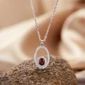 Macro detail of S925 silver necklace with oval red garnet and pavé stones pendant - Necklace / Garnet