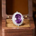 Detail view of a large oval purple amethyst ring with sparkling halo in a wooden box - Natural Amethyst Ring