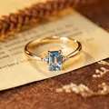 Close-up of elegant blue topaz ring with rectangular sugarcube cut on vintage book paper. - Natural Topaz Gold