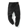 Close-up of black cotton cargo joggers with elastic waist and side pockets for men - M / Bottoms / Black