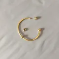 Detail shot of a golden titanium steel open bangle with an unscrewed ball end feature. - Unscrewed Ball Head DIY Open Bangle (YB-1089G) / Inner Diameter 60mm (With 2 Positioning Beads) / Gold