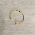 Elegant gold stainless steel ball end open cuff bracelet displayed on a light wood background - Unscrewed Ball Head DIY Open Bangle (YB-219G) / Inner Diameter 65mm / Gold