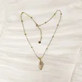 Vista detallada de un collar de acero inoxidable dorado con colgante de caracola en tela - Estilo Caracol Strass Dorado (YN-1053-B)