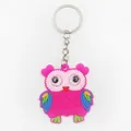 Detail view of a pink PVC owl keychain charm with colorful wings and metal ring. - Red