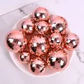 Gros plan de boules à facettes laser or rose de tailles variées sur une assiette blanche - Lot de 12 / Or rose