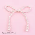 Detailed close-up of a decorative white pearl bow cake topper on a soft pink surface - Pearl Bowknot