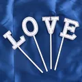 Close-up detail of elegant pearl-studded LOVE letter cake toppers on blue silk cloth - Artificial Pearl Decor (LOVE)