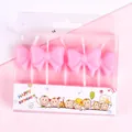 Close-up of four pink bow-shaped birthday candles in festive gift box packaging - Bowknot Shape / 4Pcs Set / Pink