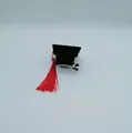 Detail showing the alligator hair clip attached to the mini graduation cap. - Mini Graduation Cap Hair Clip (LM-4789) / Black Cap with Red Tassel