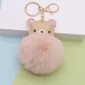 Detaillierte Nahaufnahme eines rosa Kunstfell-Bommel-Schlüsselanhängers mit Bär - Goldene Kettenschließe / Nude