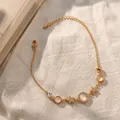 Goudkleurige armband met kattenoogstenen en delicate sterrenhangers. - Ster Kattenoog / Goud