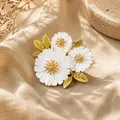 Exquisite Nahaufnahme einer weißen Gänseblümchen-Brosche mit goldenen Blättern auf Leinen - Gänseblümchen-Stil (XZ1330)