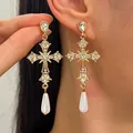 Dettaglio di orecchini a croce gotica con strass brillanti e gocce di perla elegante - Stile Croce con Strass Dorata con Perla a Goccia / Oro (Oro KC)