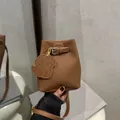 Elegant brown pebbled leather bucket bag featuring a dog charm and buckle strap. - Brown