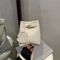 Stylish cream-colored mini bucket bag featuring a cute puppy charm and buckle strap - White