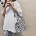 Stylish black and white zebra pattern tote bag with a cute plush bear charm on model - Zebra Print (Bag Only) / Zebra Print