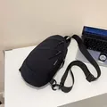 Detail view of the black nylon minimalist chest bag with adjustable strap on a desk - Black