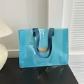 Stylish light blue transparent jelly tote bag with durable dark blue nylon handles. - Blue