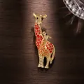 Close-up of gold enamel giraffe brooch with red and orange spots on dark wood - Red
