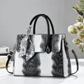 Detailansicht einer eleganten Tragetasche mit Schlangenmuster in Schwarz-Weiß und einem Seidentuch. - Einzelbag-Stil / Weiß