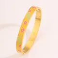 Detailed macro view of an enamel floral pattern on a gold stainless steel bangle - Pink Flower Pattern Gold Bangle