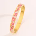 Detailed macro view of a gold-plated stainless steel bangle with pink enamel patterns - Pink and White Pattern Gold Bangle