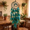 Handmade teal feathered dreamcatcher with tree of life and moon motif hanging in a room - Dream Seeker / 15-70cm