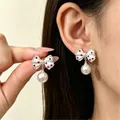 Elegant white bow earrings with red polka dots and dangling pearl shown on model's ear - Artificial Pearl Polka Dot Bow Drop (A-452)