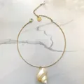 Detail van een gouden choker ketting met een natuurlijke schelphanger en witte parel. - Stijve Choker Schelp Hanger / 38+5cm
